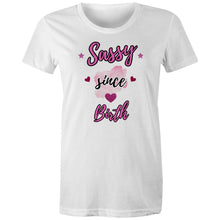 Load image into Gallery viewer, White organic cotton t-shirt with “Sassy Since Birth” printed in bold pink and black text, featuring hearts, stars, and a pink watercolour splash design.
