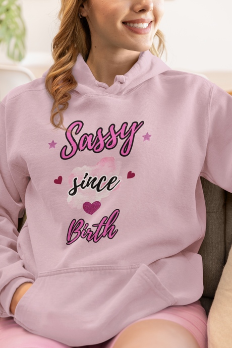 Person wearing a pink hoodie with 'Sassy since birth' text